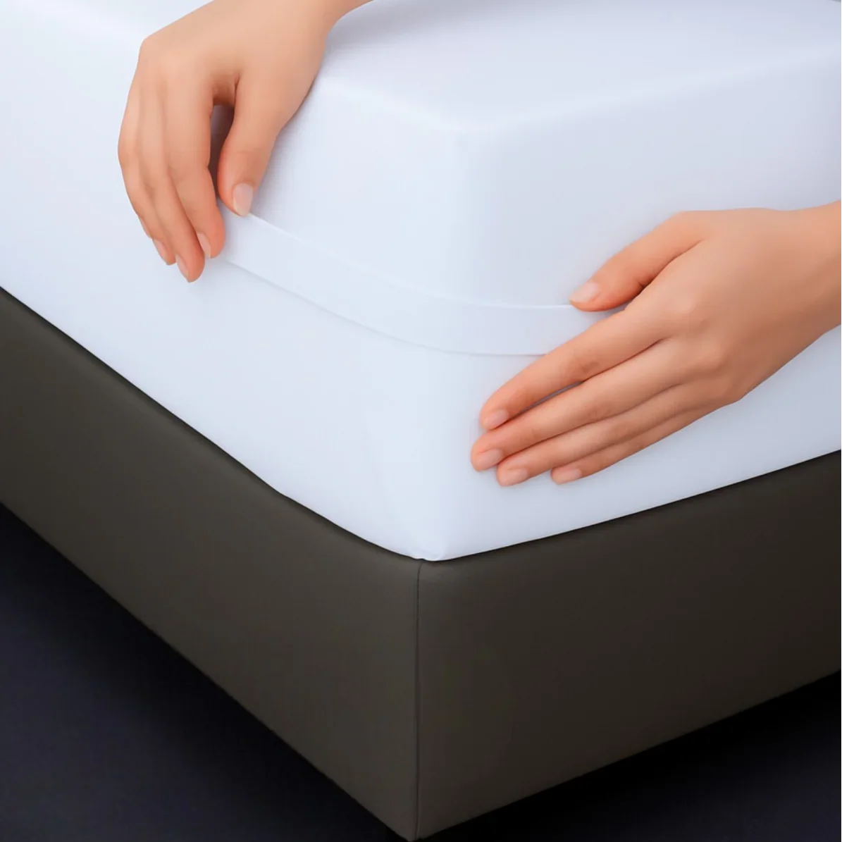 Hands putting on a white fitted mattress protector on a bed